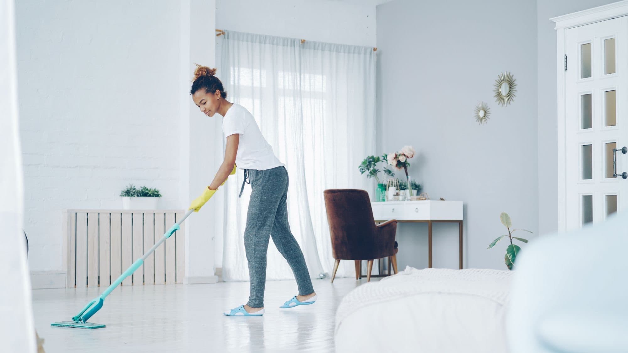 Reinigungskraft wischt den Boden einer hellen Wohnung